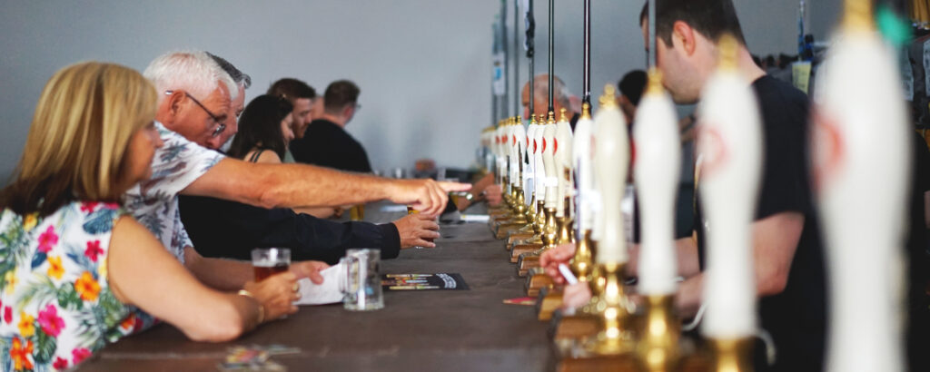 Customer choosing a beer at the Camra beer festival from a row of beer engines