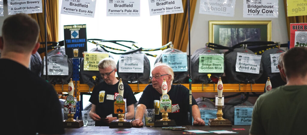 Beer stand at Camra beer festival, with two men and hand pumps for cask ale